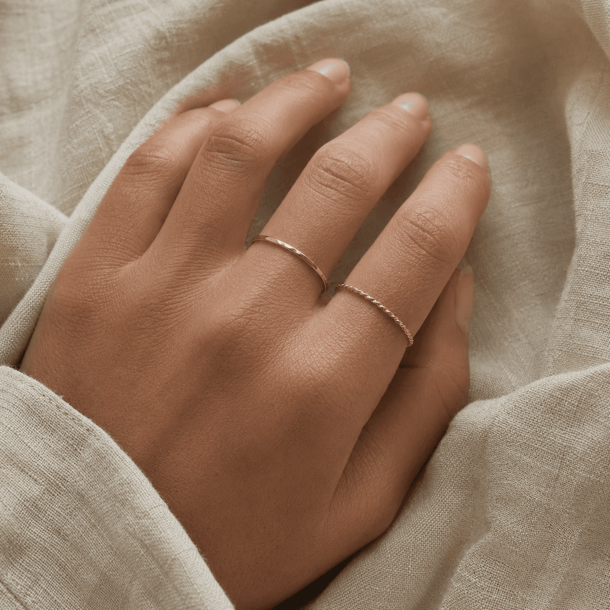 Empty-cart category pick: hand on warm linen wearing two thin stacking rings.